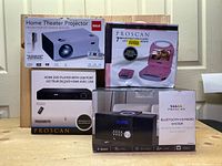 Photo showing RCA Home Theater Projector box (white), Proscan 7-inch Portable DVD Player pink box, Proscan HDMI DVD Player box including remote, and Proscan Bluetooth CD Micro System box.
