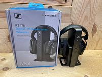 Box and headphone set on transmitter stand against wood background