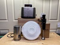 Lot contents showing the toaster on a box, milk frother on the left, blender with mixing bowl lid in front, all cords visible.