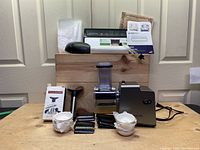 Full set of kitchen appliances and accessories displayed including vacuum sealer, slicer, ramekins, can opener, and wine pump on wood surface.