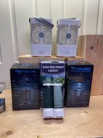 Two portable air coolers on top of wooden surface with three boxed solar bug zappers and one unboxed lantern-style zapper