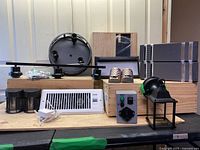 Photo of all lot items arranged including white register fan, wall sconces, outdoor lantern, 3-bulb rail fixture, solar lights, nightlights, address light, generator transfer switch, and circular fixture.