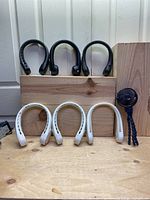 Seven fans total: 3 white neck fans, 3 black neck fans, and 1 blue mini fan with flexible tripod. Arranged on wooden background.