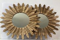 Set of two sunburst wall mirrors overlapping on white background, front side showing mirror and gold wooden textured frames