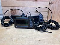 Three identical endoscope units front-facing on wooden surface