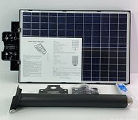 Solar panel, mounting pole, remote control, mounting bracket, connectors, and instruction sheet laid out on white surface.