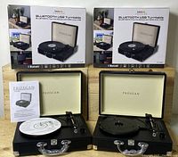 Two Proscan Bluetooth USB turntables displayed with open lids, user manuals, software CDs, and original boxes behind.