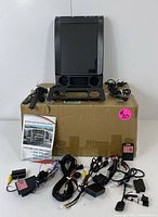 Full lot showing the large vertical 12.1-inch touchscreen navigation system displayed above several wiring harnesses and components, placed on a cardboard box.