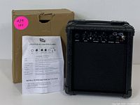 Compact black G-5 guitar amplifier with original box and instruction sheet showing layout and controls.