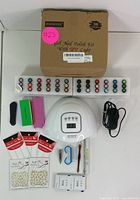 Complete nail art kit spread showing all gel polishes, nail lamp, manicure tools, nail art decals and adapter
