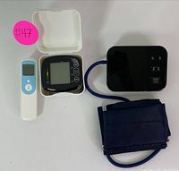 Complete set showing the blood pressure monitor in its case alongside the infrared thermometer, with the cuff attached and digital display visible.