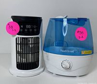Front view of the digital space heater with black top and digital display next to blue and white Peach Street humidifier.