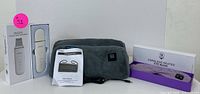 Facial therapy set items including ultrasonic scrubber box, heated eye mask in soft gray fabric, instructions, and a packaging box for eye mask.