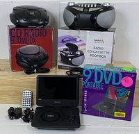 Photo of the portable DVD player with open screen, remote control, two CD boomboxes with boxes and cords included