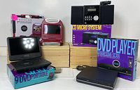 Photo shows the two portable DVD players, standard DVD player, and CD micro system, including original boxes and the devices themselves.