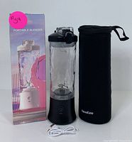 Black and clear portable blender with box and black carrying case, front view