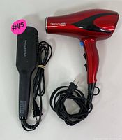 Top-side view of the red Testanera hair dryer and black Megawise heated straightening brush laid flat with cords shown