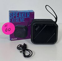 Black compact Speaker Extreme Bluetooth speaker with carrying strap, USB cable, and original box displayed together on a white background.