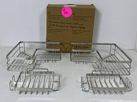 Four stainless steel shower caddies with hooks displayed alongside their packaging box.