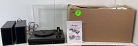 Full set of turntable system showing 3-speed turntable, dual external speakers, clear dust cover, user manual, and original packaging box.