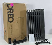 Oil-filled radiator heater with box, remote control, caster wheels, user manual, and power cord.