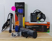 Front view of aquarium heaters and submersible filtration pump with boxes and cords displayed on wooden surface