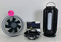 Camping fan, LED lantern, and headlamp set arranged side by side.