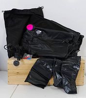 Black water bag, shower components, and drawstring storage bag on wooden surface