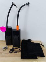 Two black portable air compressors with flexible hoses and digital control panels, displayed upright with accessories on a wooden surface.