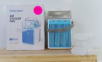 Portable air cooler fan next to its box showing the 800ml water tank capacity and product branding.