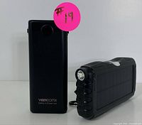 Two portable power banks side by side, one Veekomx brand and one solar with flashlight
