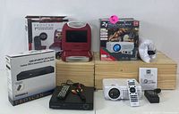 Photo showing the entire home entertainment bundle including 7" red portable DVD player, boxed black HDMI component DVD player, mini projector with remote and accessories on top of a wooden crate.
