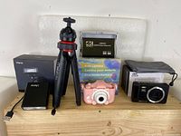 Photo showing all items: mini camera speedlite, kids camera, 4K Ultra HD camera, portable mini tripod, USB 4K HDMI video capture device, external battery pack, and boxes.