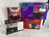 Lot showing all boxed items: 15.6 inch Portable DVD Player, Retro CD Radio Boombox, and Bluetooth CD Micro System.