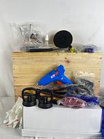Full kit laid out on wooden background, showing glue gun, suction cups, gloves, pry tools, glue sticks and accessory bags