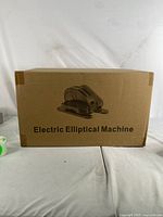 Front view of sealed cardboard box labeled 'Electric Elliptical Machine' with printed image of the elliptical.