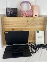 Full lot including iPad Air keyboard case open, Helmet Wireless Earphone box, pink headphones, power bank, and cable on wooden background.