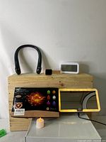 Photo showing all items in lot - neck fan, smart watch, digital alarm clock, LED vanity mirror, and box of flameless tea lights with one light displayed