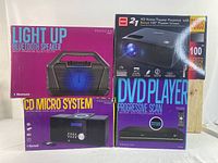 Photo of lot boxes: Light Up Bluetooth Speaker, CD Micro System, HD Home Theater Projector with Bonus Screen, and DVD Player