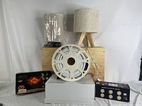 Table lamps, LED strip lights on a reel, puck lights box, flameless tea lights set visible arranged on white and wooden background.