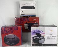 Four electronic items displayed in original boxes - two CD radio boomboxes, one CD/cassette radio boombox, and one HDMI upconvert DVD player