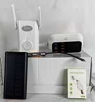 Shows the power bank, wireless extender, multi-port adapter with USB ports and digital display, and the watch wireless charger in its box.