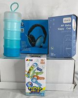 Photo showing blue travel food container, blue baby safety earmuffs box, Oberni PP Baby Sippy Cup box, and Popkey Pals interactive toy key fob box.