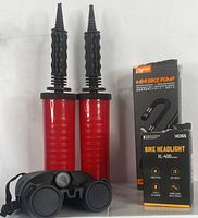 Two red mini bike pumps with black handles and nozzles, XOSS bike headlight box and device