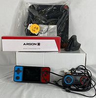 Full lot view showing gaming console, controller, adapter, mouse pad, and ergonomic mouse.