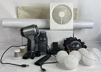 Full lot showing handheld vacuum, attachments, desk fan, rolls of flooring, pillow covers, and solar string lights