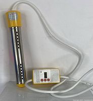 Portable water heater with yellow and stainless steel body and attached control panel lying on white surface.