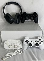 Lot contents showing Skullcandy headphones and three gaming controllers: one black wireless and two white wired controllers, one with USB cable.