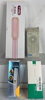 Photo of all four boxed items: TYMO Ring hair straightener brush, mini fan, portable hair remover, and Xlife ear cleaner
