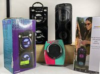 Lot contents including two Bluetooth party speakers in black with LED lights and a portable CD player in packaging.